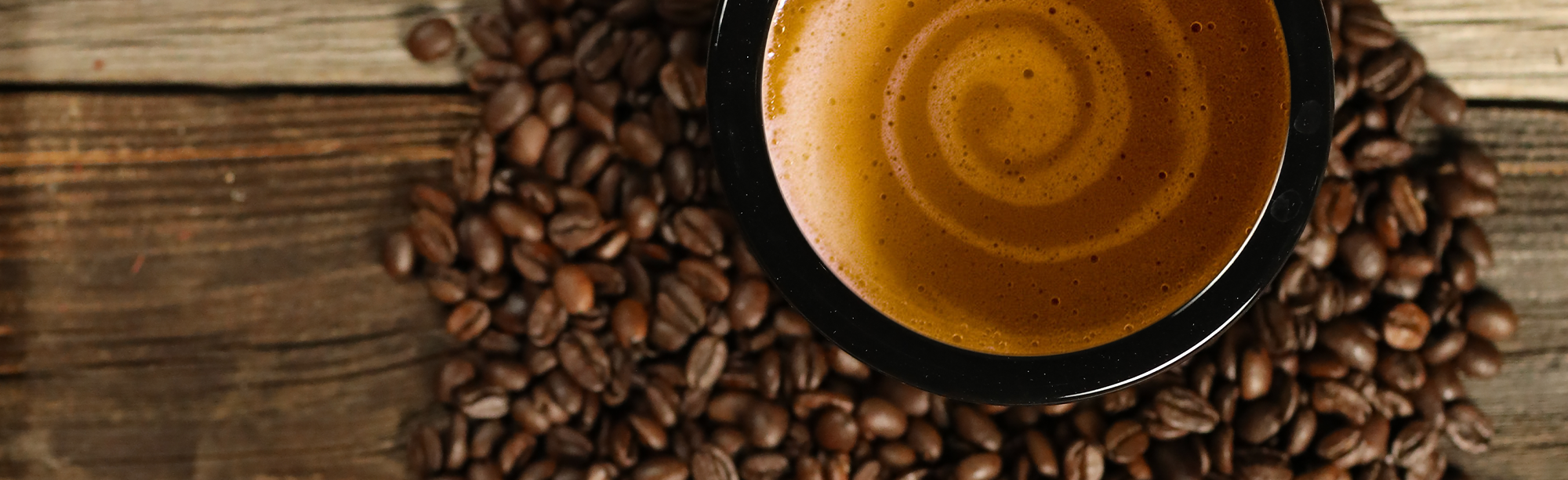 Image of coffee beans and coffee mug with milk swirl | Finger Lake Coffee Roasters Canandaigua, NY